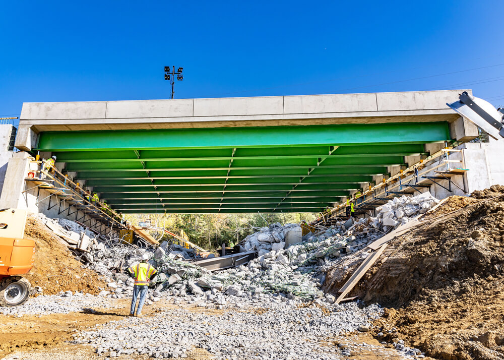 A worker surveys the final placement of a bridge section on Buckingham Heavy Transport's accelerated bridge construction project
