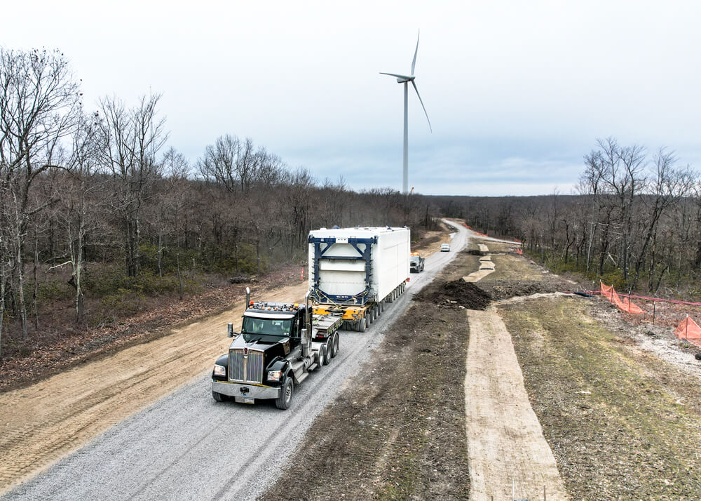 Loaded Buckingham semi and trailer with wind turbine in the background