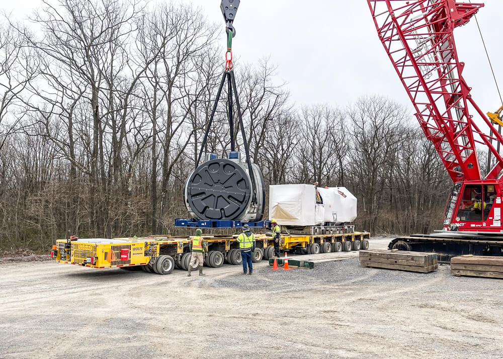 A crane sets a wind turbine component onto a trailer for Buckingham Transport