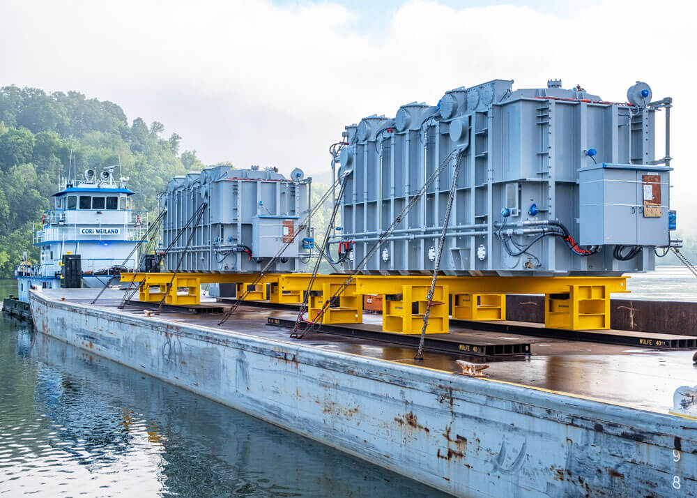 Two Transformers sit on a barge ready to be offloaded for delivery