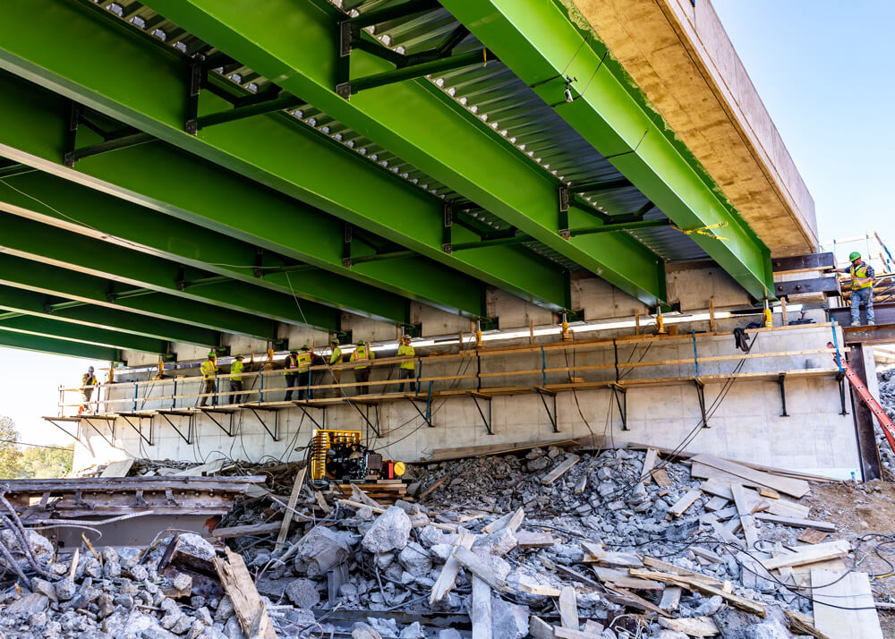 Buckingham jacks are lined up under girders on accelerated bridge replacement project