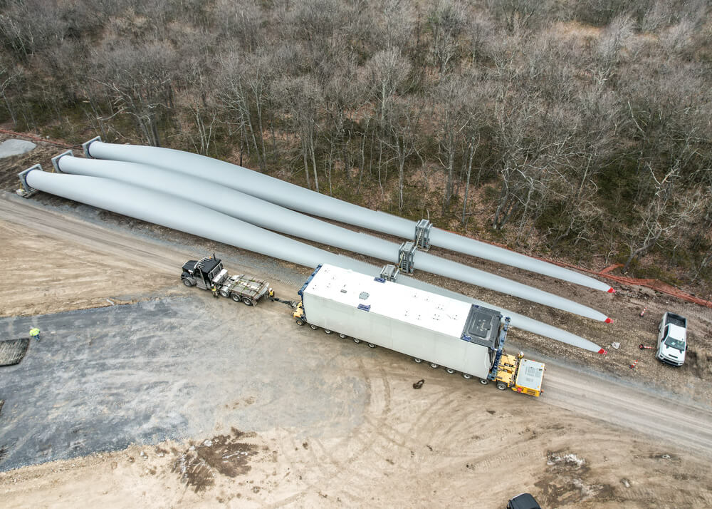 Aerial view of three wind turbine blades with Buckingham Transport's loaded Goldhofer trailer beside them